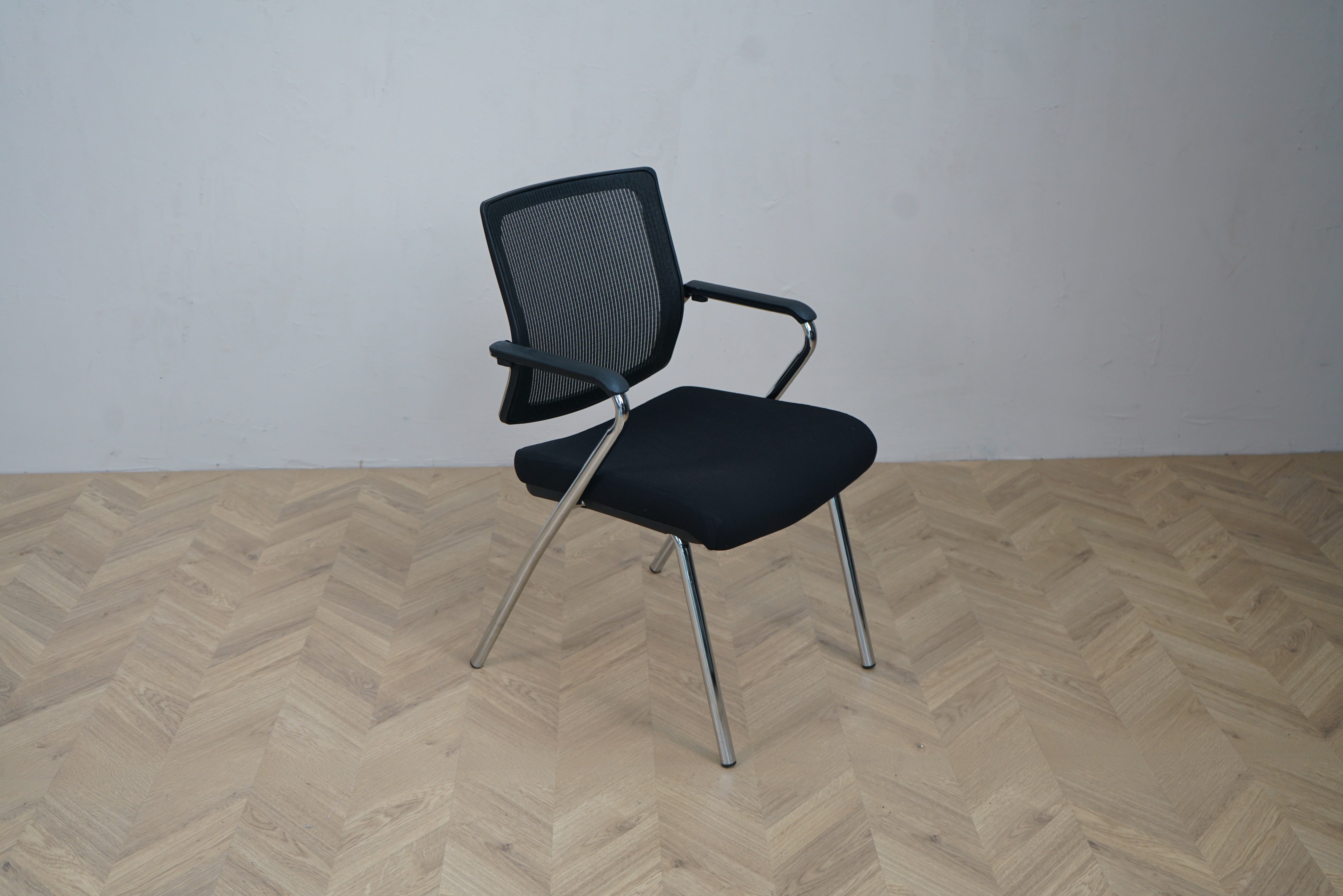 Sintec X mødestol i sort med blankt stålstel set fra siden. Åndbar netryg og tykpolstret sæde.